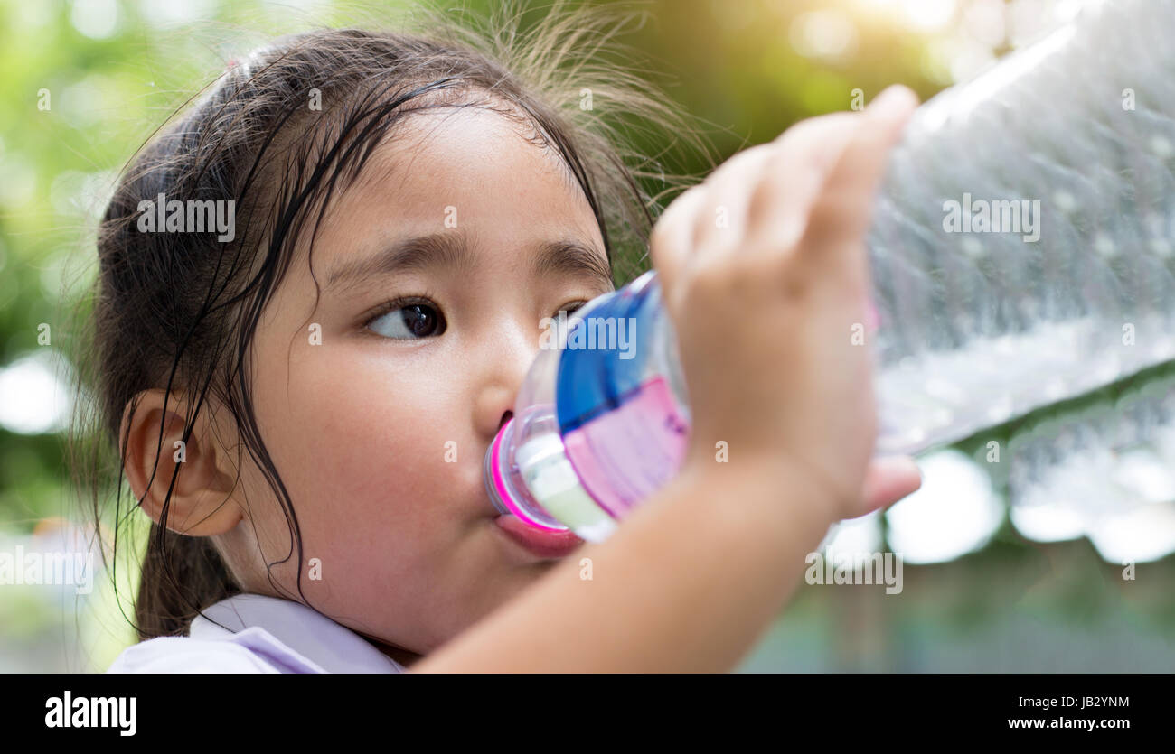 Asiatin Bottom-up-Trinkwasser mit Kunststoff-Flasche im Park heißen Tag Stockfoto