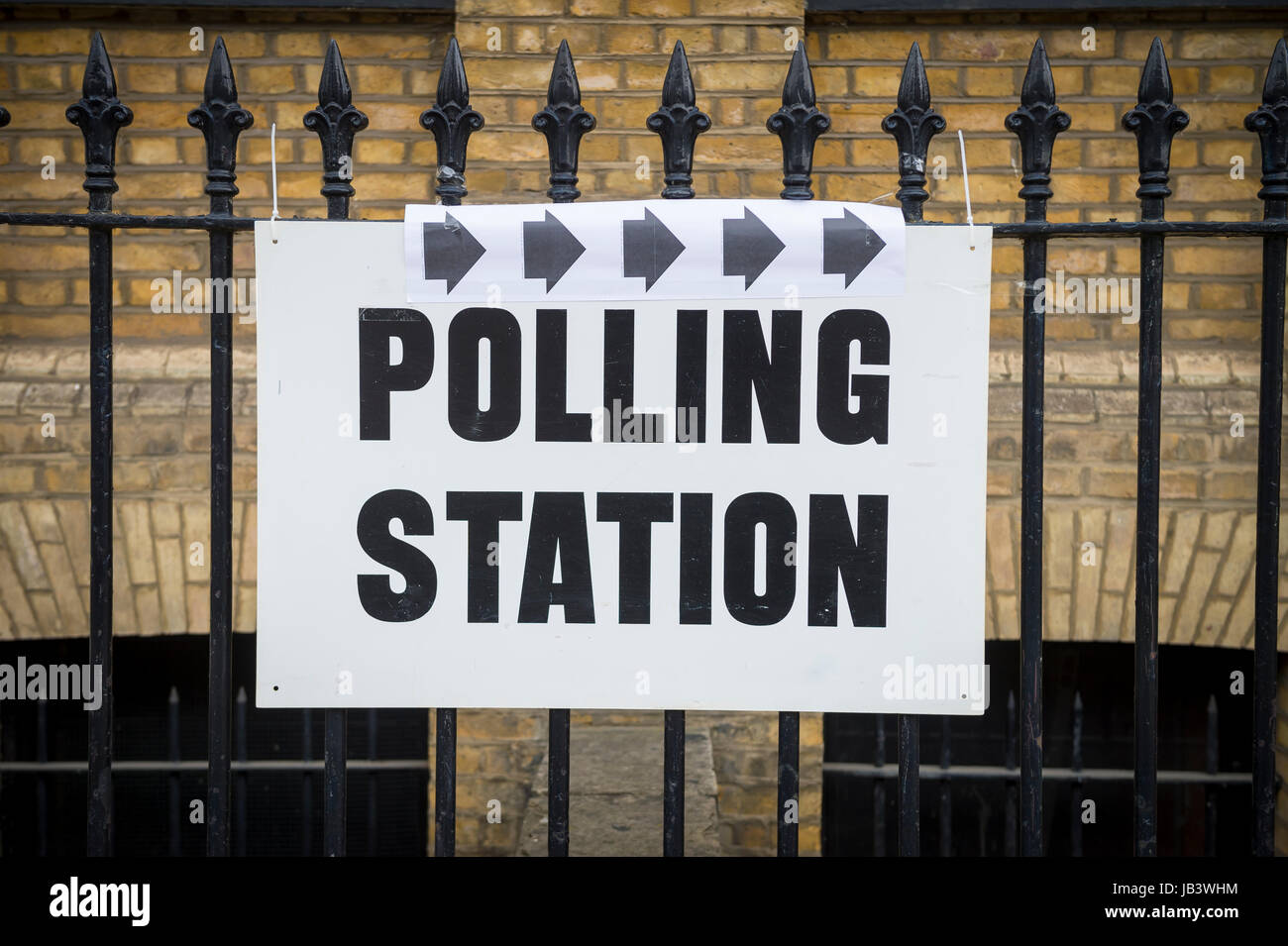 Wahlen in Großbritannien Wahllokal Schild hängen auf klassische Schmiedeeisen Zaun vor der gelben Wand in London, UK Stockfoto
