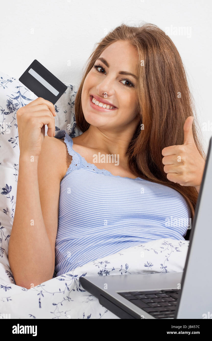 Junge Glückliche Frau Mit Kreditkarte Beim Online-shopping Im Bett zuhause Stockfoto