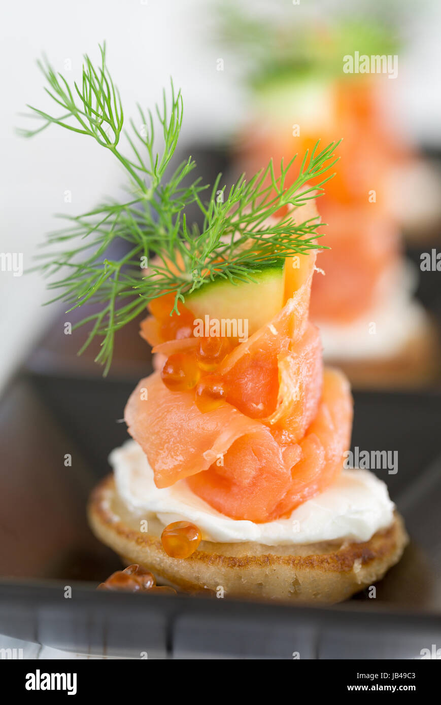 Blini mit geräuchertem Lachs und saure Sahne, garniert mit Dill und ...
