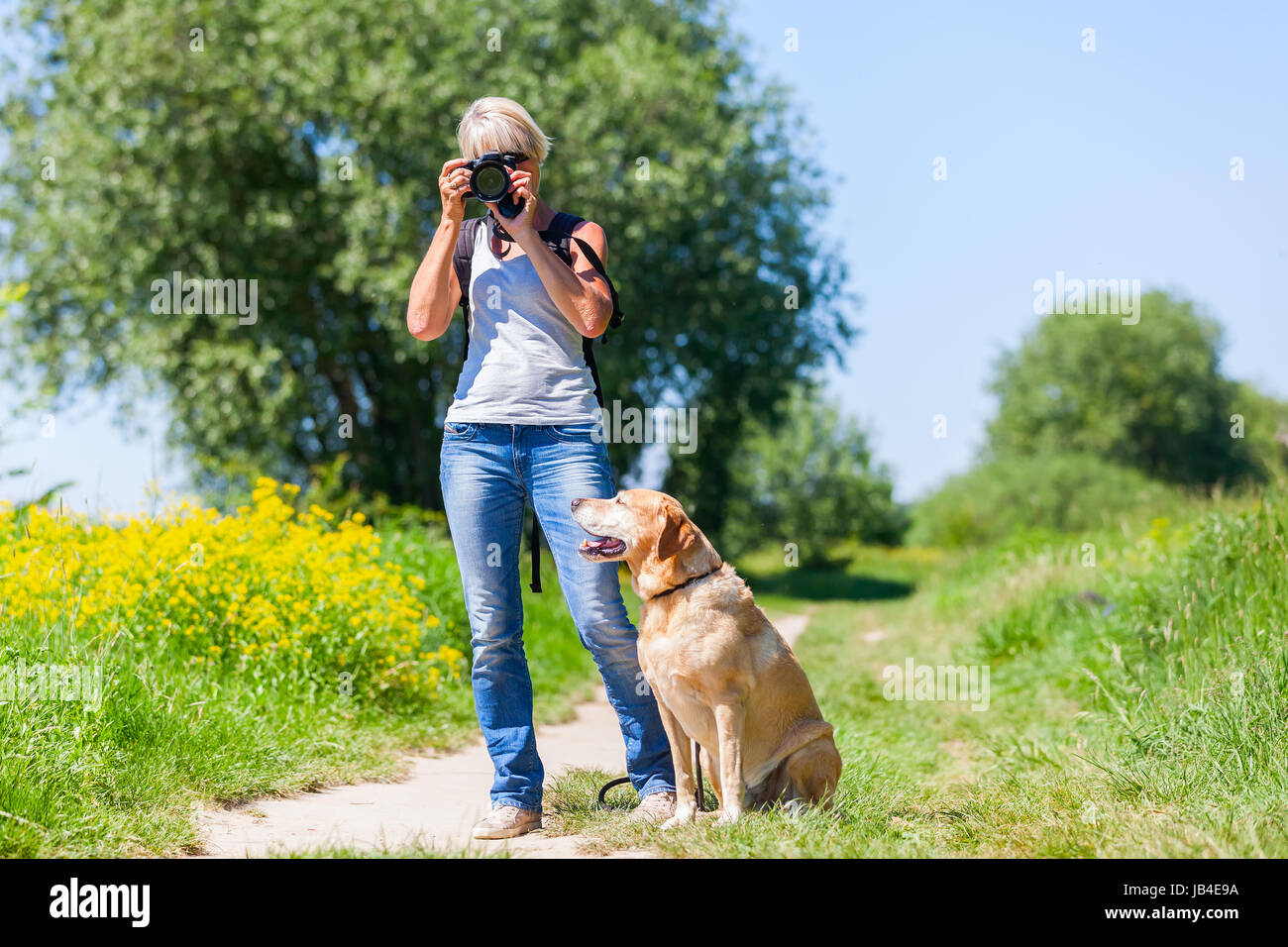 Reife Frau mit einem Labrador-Retriever fotografieren mit einer Kamera während einer Wanderung Stockfoto