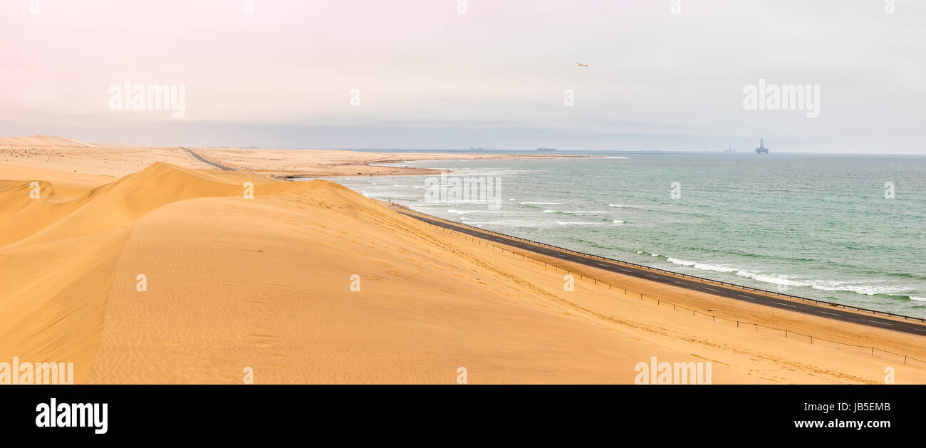 Lange Straße über Dünen der Kalahari-Wüste mit atlantischen Küste in der Nähe Stadt Swakopmund, Namibia Stockfoto