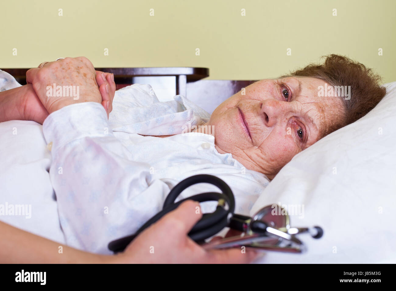 Bild von einem Bett geritten ältere Frau mit ihrer Pflege hält ein Stethoskop Stockfoto
