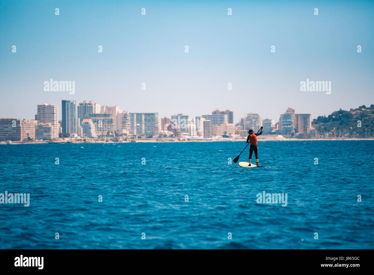 Eine Person auf einem feilbieten Board in Richtung der Stadt, am Horizont, mit Gebäuden und eine Skyline Stockfoto