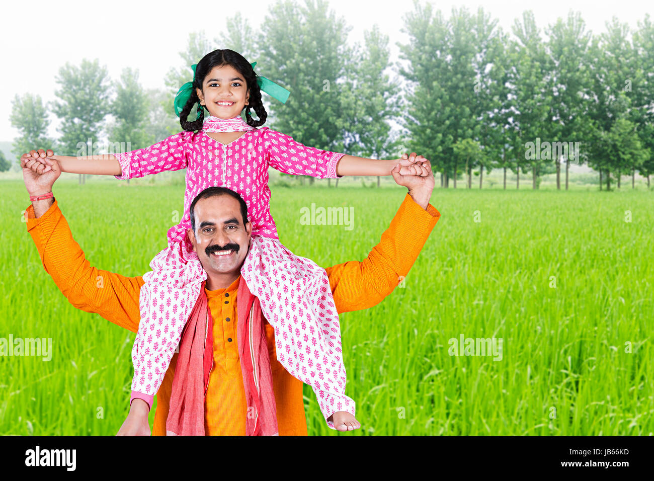 Portrait von Happy indischen Bauern, die kleine Tochter auf den Schultern auf der Farm Stockfoto