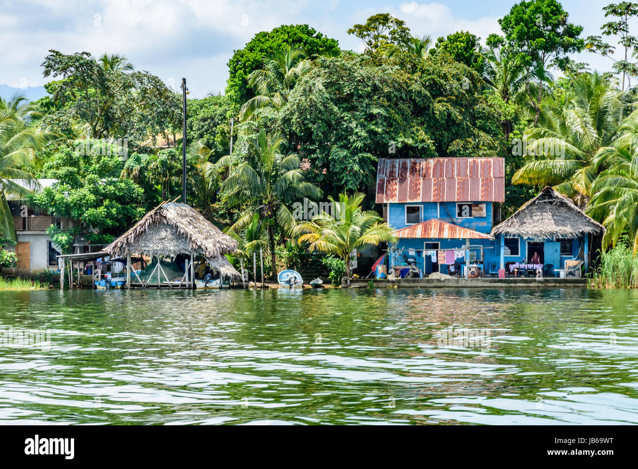 Rio Dulce, Guatemala - September 1, 2016: Holzhäuser mit Zinn & palm leaf Dächer am Ufer des Rio Dulce, Guatemala, Mittelamerika Stockfoto