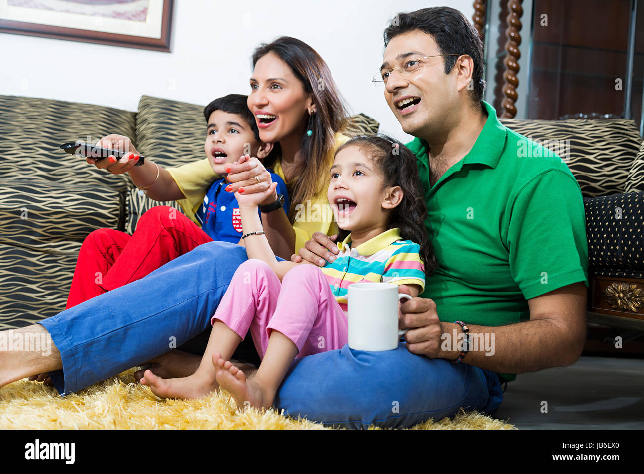 4 Personen junge Mädchen Kinder Eltern lächelnd Tee Fernseher sitzend beobachten Stockfoto