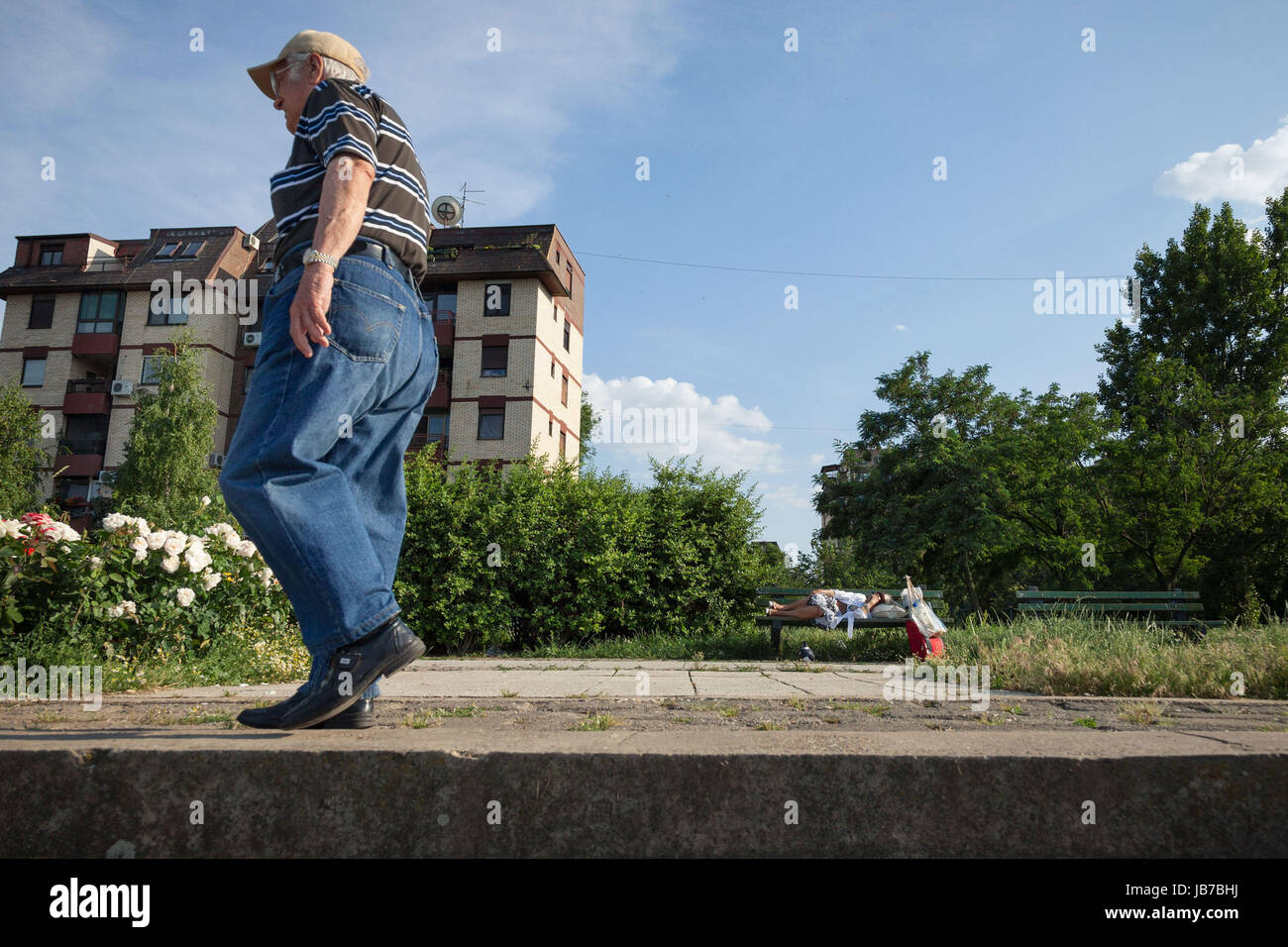 Belgrad, Serbien - 3. Juni 2017: Alter Mann zu Fuß in der Nähe von einem senior Frau schläft auf einer Bank, im Bezirk von Doni Dorcol, Belgrad-Bild von einem ol Stockfoto