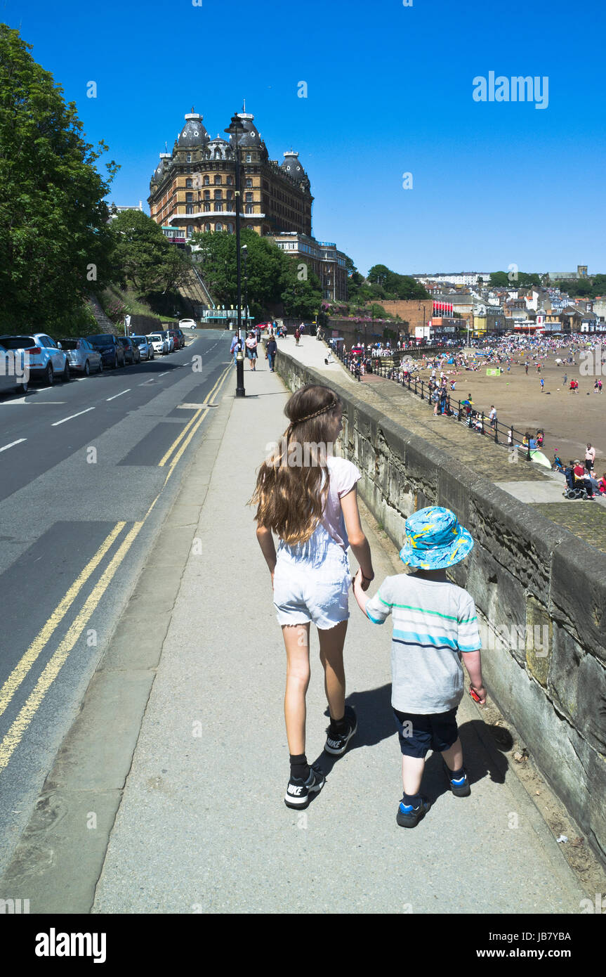 Dh South Bay Scarborough North Yorkshire Mädchen und Jungen halten sich an den Händen zu Fuß am Strand suchen Stockfoto