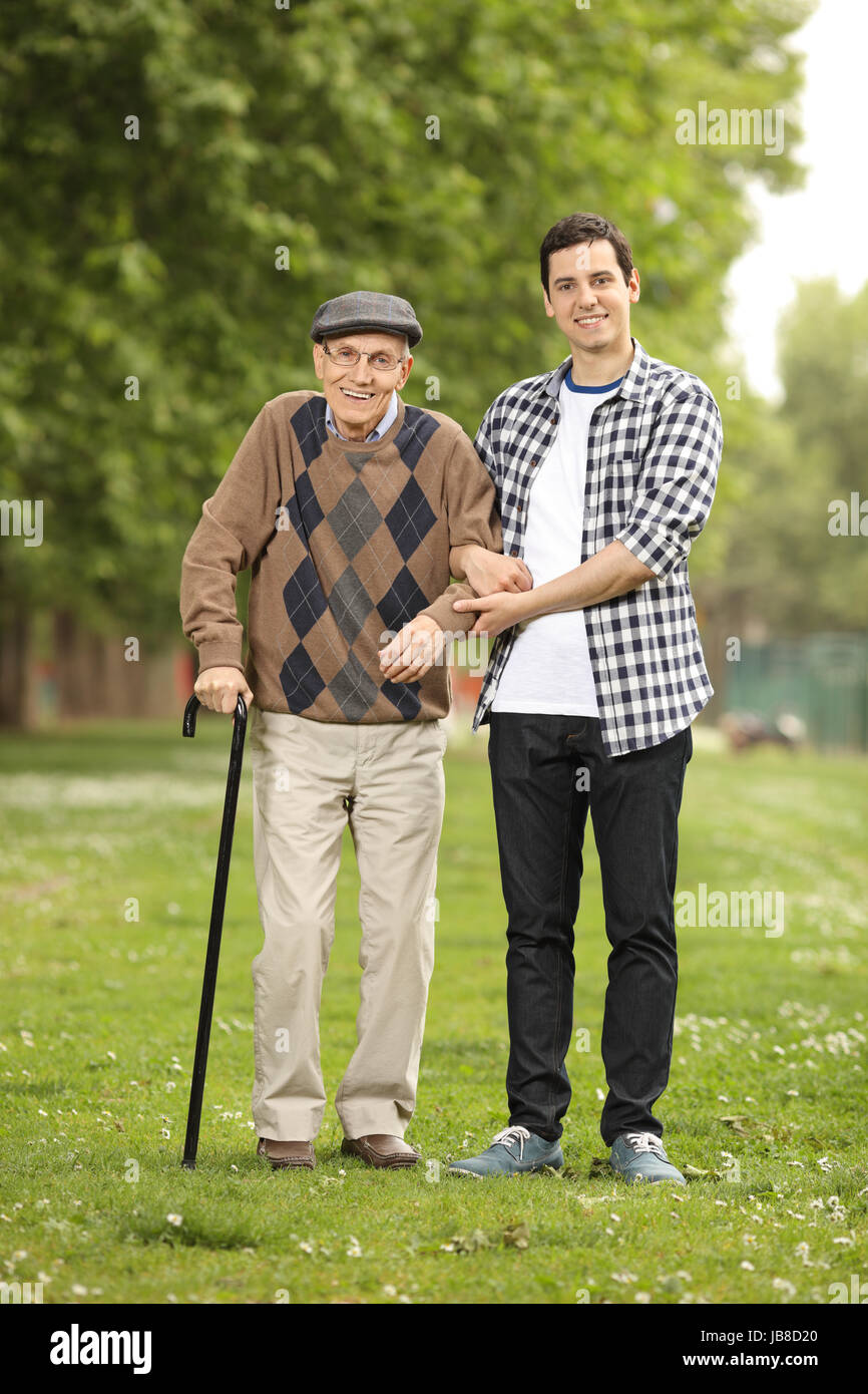 In voller Länge Portrait von einem Enkel hilft seinem Großvater im park Stockfoto