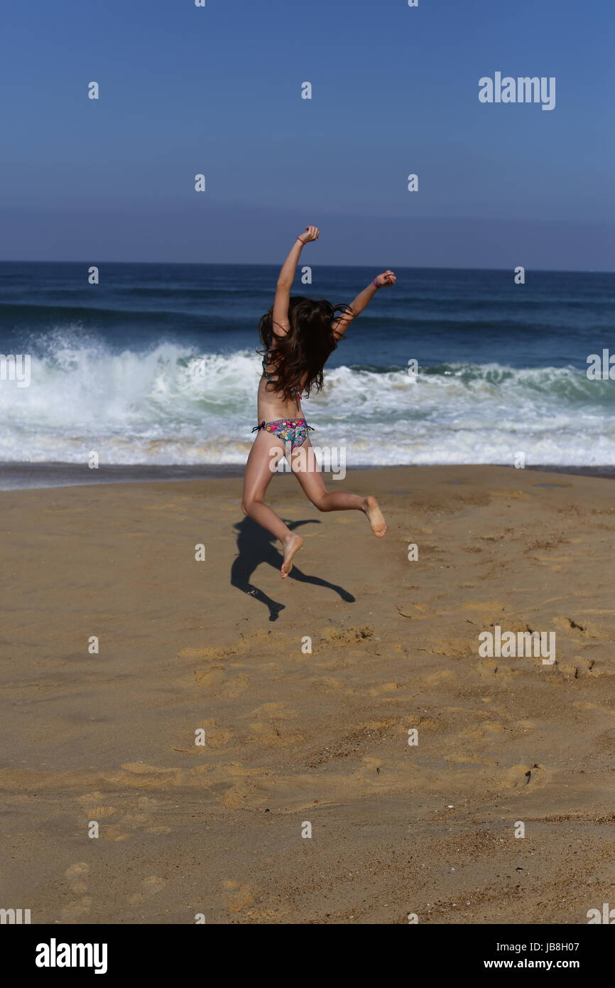 Springen vor Freude in die Luft am Strand am Meer am Strand von Messanges, Frankreich Stockfoto