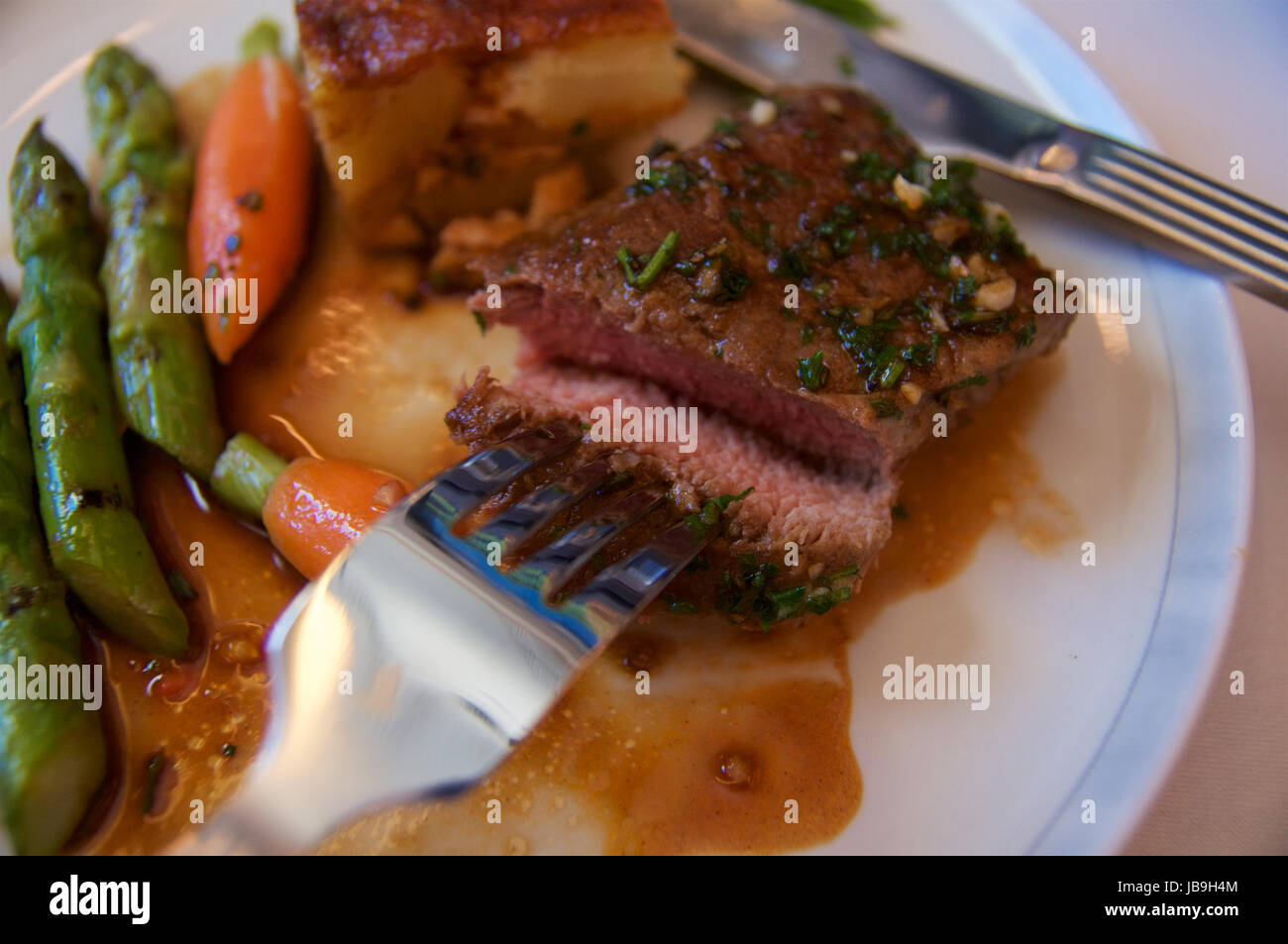 SINGAPORE AIRLINES, Singapur - 22. Juli 2016: Gegrilltes Lammfilet in Rosmarinjus mit Karotten, Spargel, Cherry-Tomaten und Kartoffelgratin in Busine Stockfoto