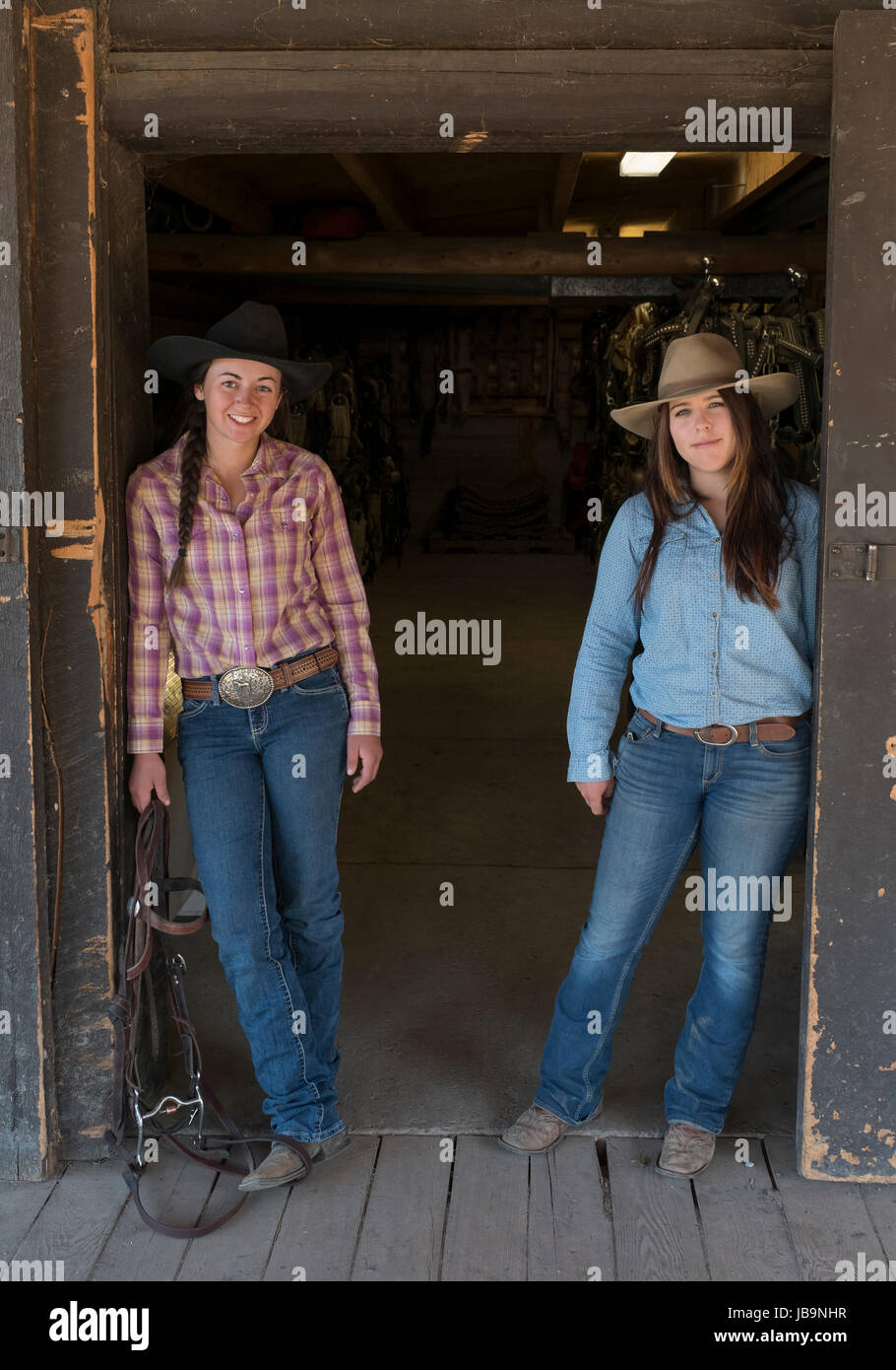 Zwei junge weibliche "Dude Ranchers' posieren für ein Foto vor der Sattelkammer an der Herz sechs Ranch in der Nähe von Moran Junction, Wyoming, USA. Stockfoto