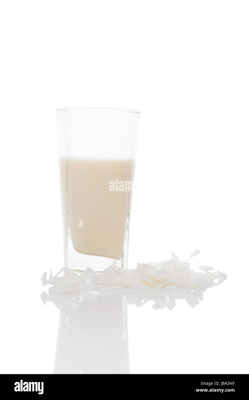 Kokosmilch aus Glas mit Kokosflocken isoliert auf weiss. Vegane Milch Konzept. Stockfoto