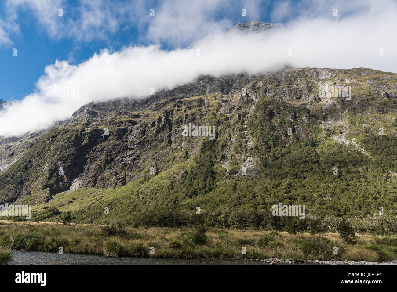 Fiordland-Nationalpark, New Zealand - 16. März 2017: Landschaft der Affe Bach fließt im Tal unter hohen Berggipfel teilweise bedeckt mit weißen c Stockfoto