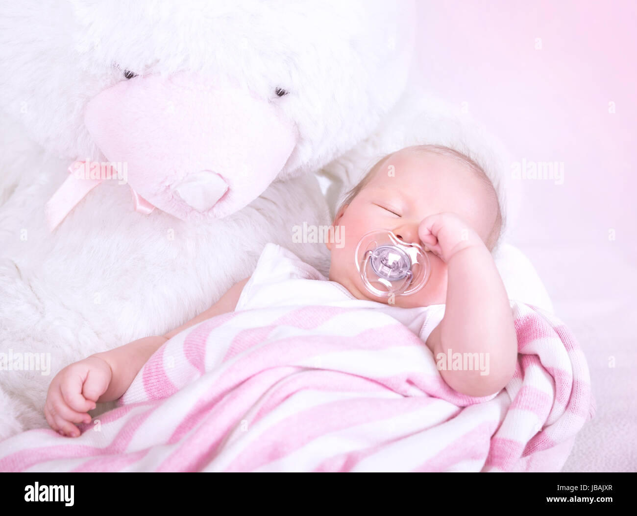 Niedliche neugeborenes Baby mit Schnuller im Mund, auf großen weißen Stofftier Teddybär