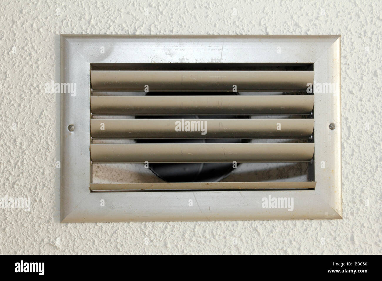 Kleiner Silber Metall HVAC air Vent mit fünf Latten in die weiße strukturierte Decke eines alten Hauses hautnah. Stockfoto