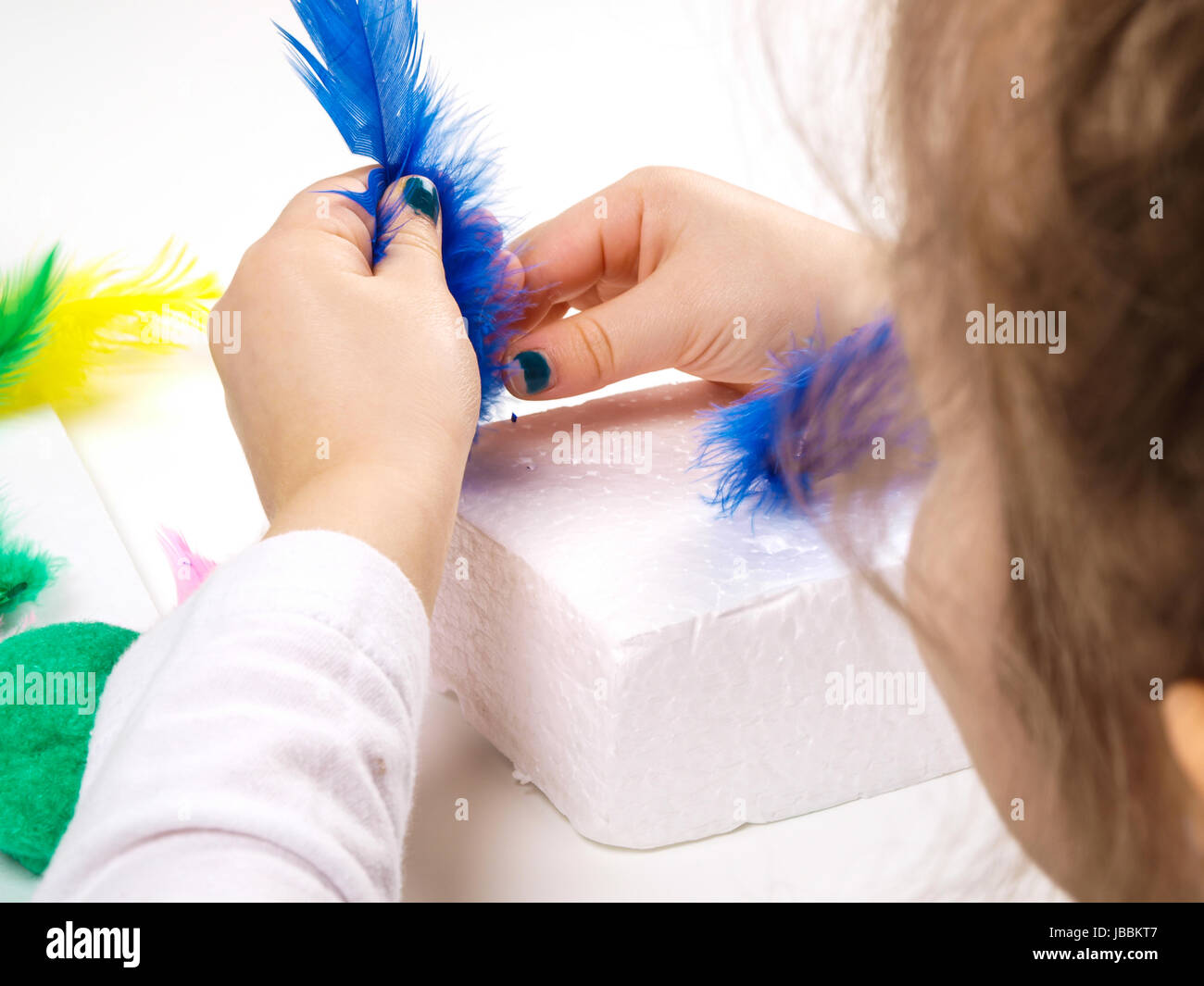 Kleine Mädchen Hände spielen mit bunten Federn, Oster-Deko zu schaffen Stockfoto