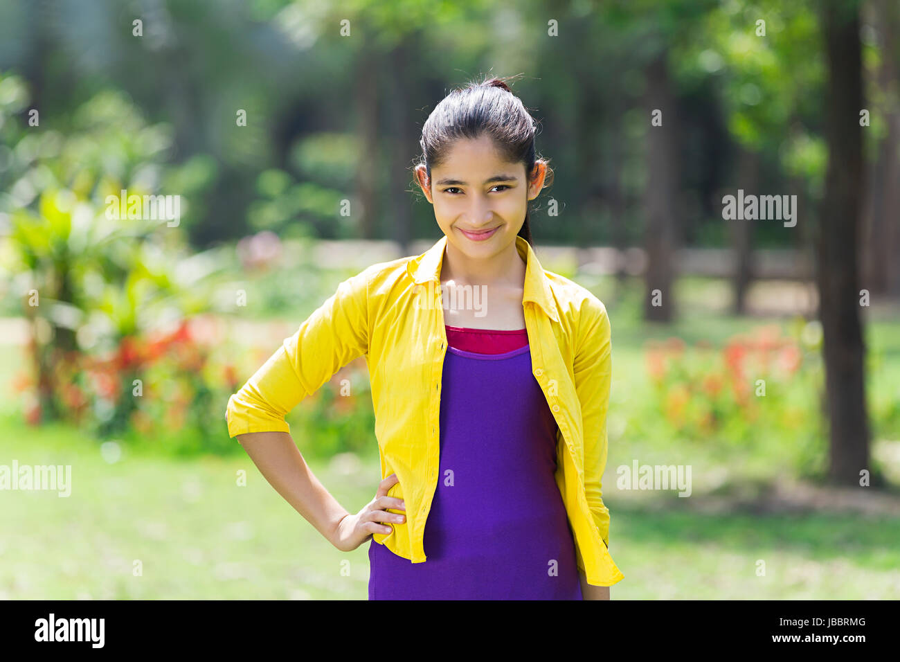 Schöne 1 indische Mädchen stehen Hand-auf-hip in Park lächelnd Stockfoto