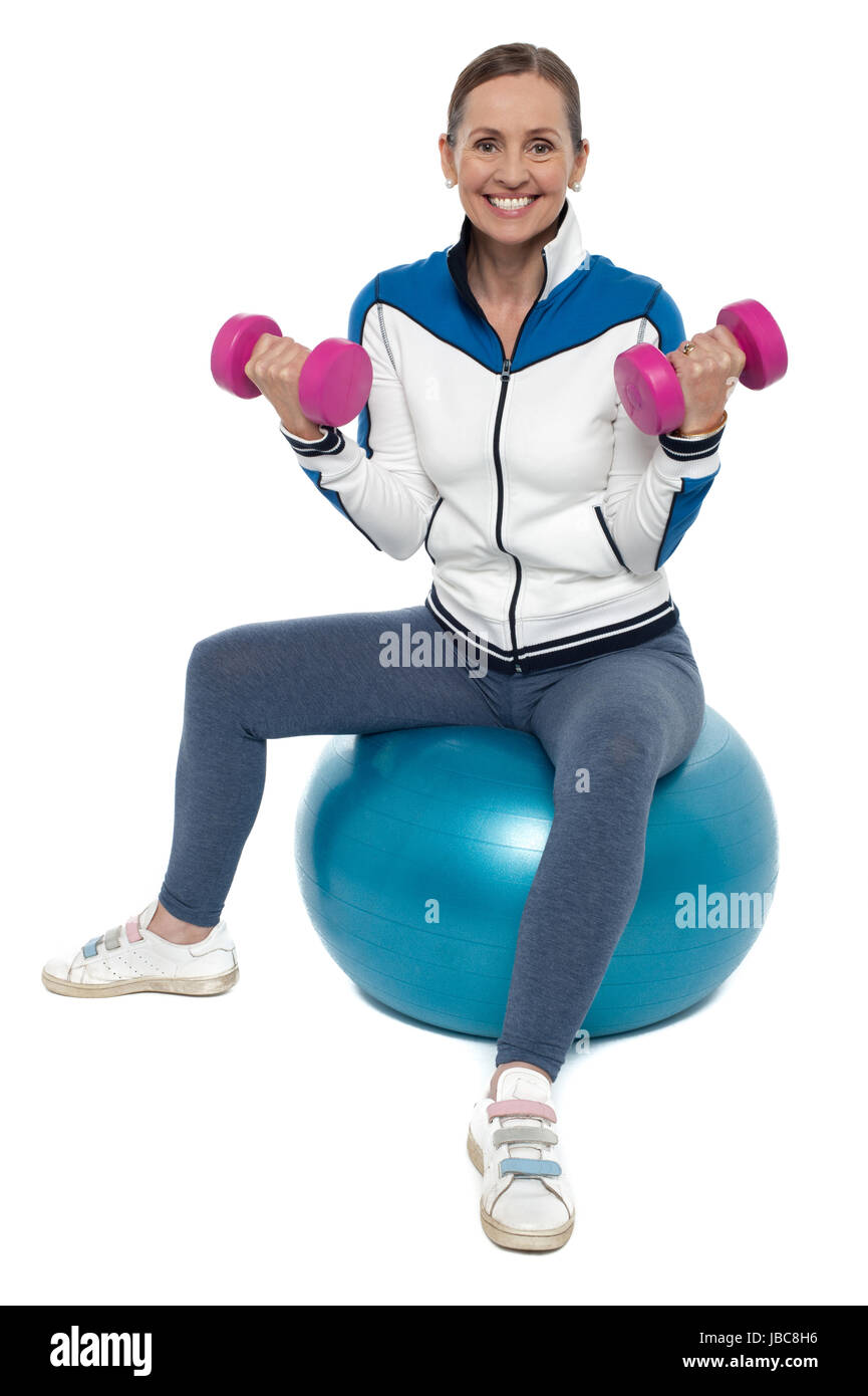 Mittleren Alters fit Frau sitzend auf einem Fitness-Ball mit Hanteln trainieren. Stockfoto