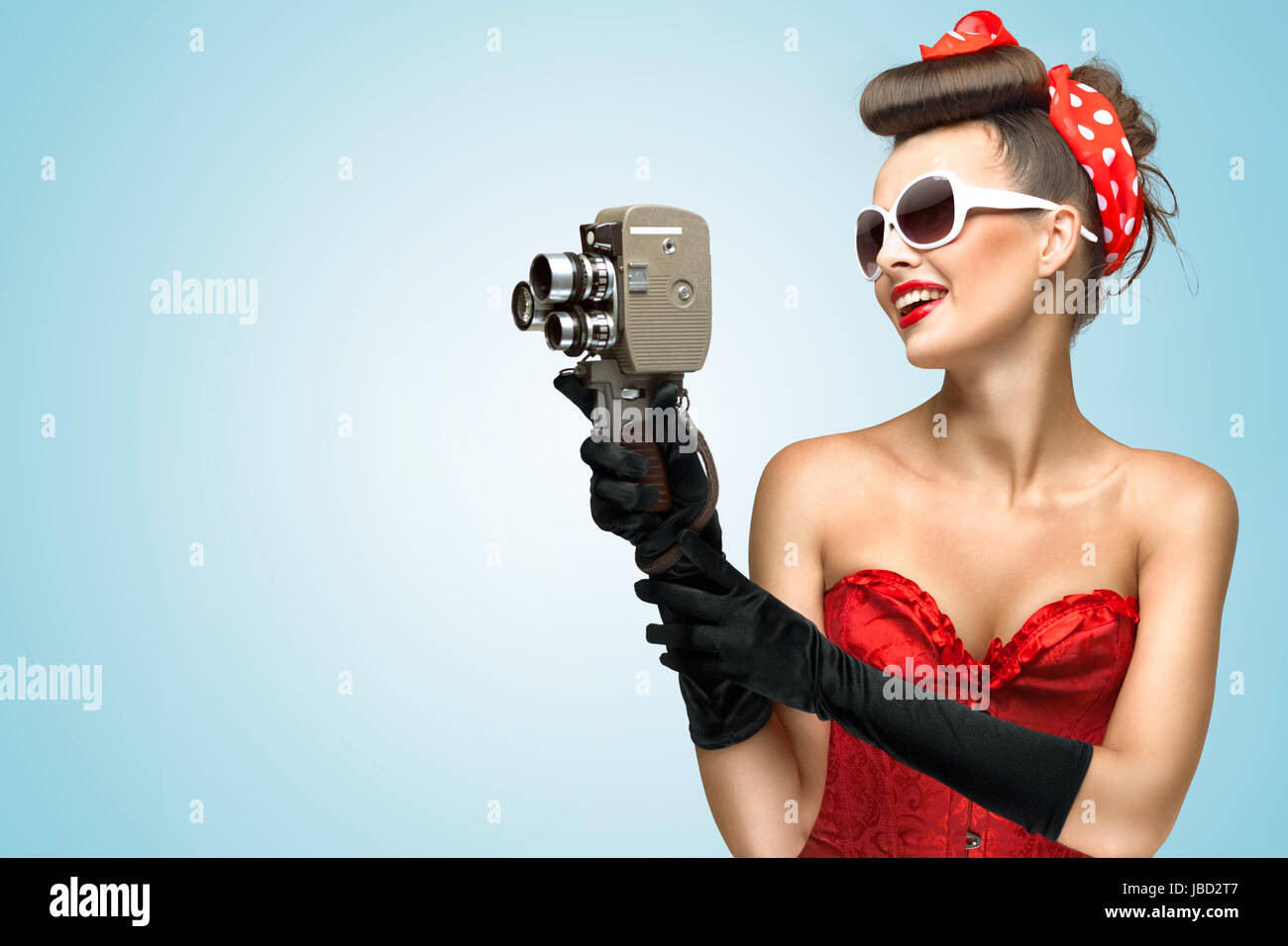 Ein Foto von der Pin-up-Mädchen in Korsett und Handschuhe Vintage 8mm Kamera halten. Stockfoto