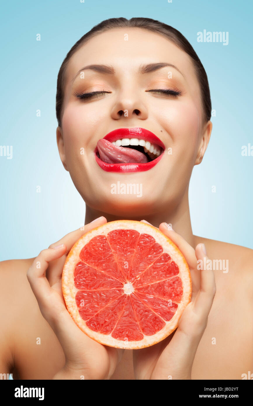 Ein kreativer Porträt eines schönen Mädchens mit roter Grapefruit und eine sexy Zunge. Stockfoto