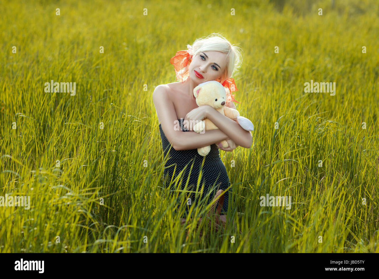 Umarmt eine Spielzeug Mädchen tragen in einem Feld hohem Gras. Stockfoto