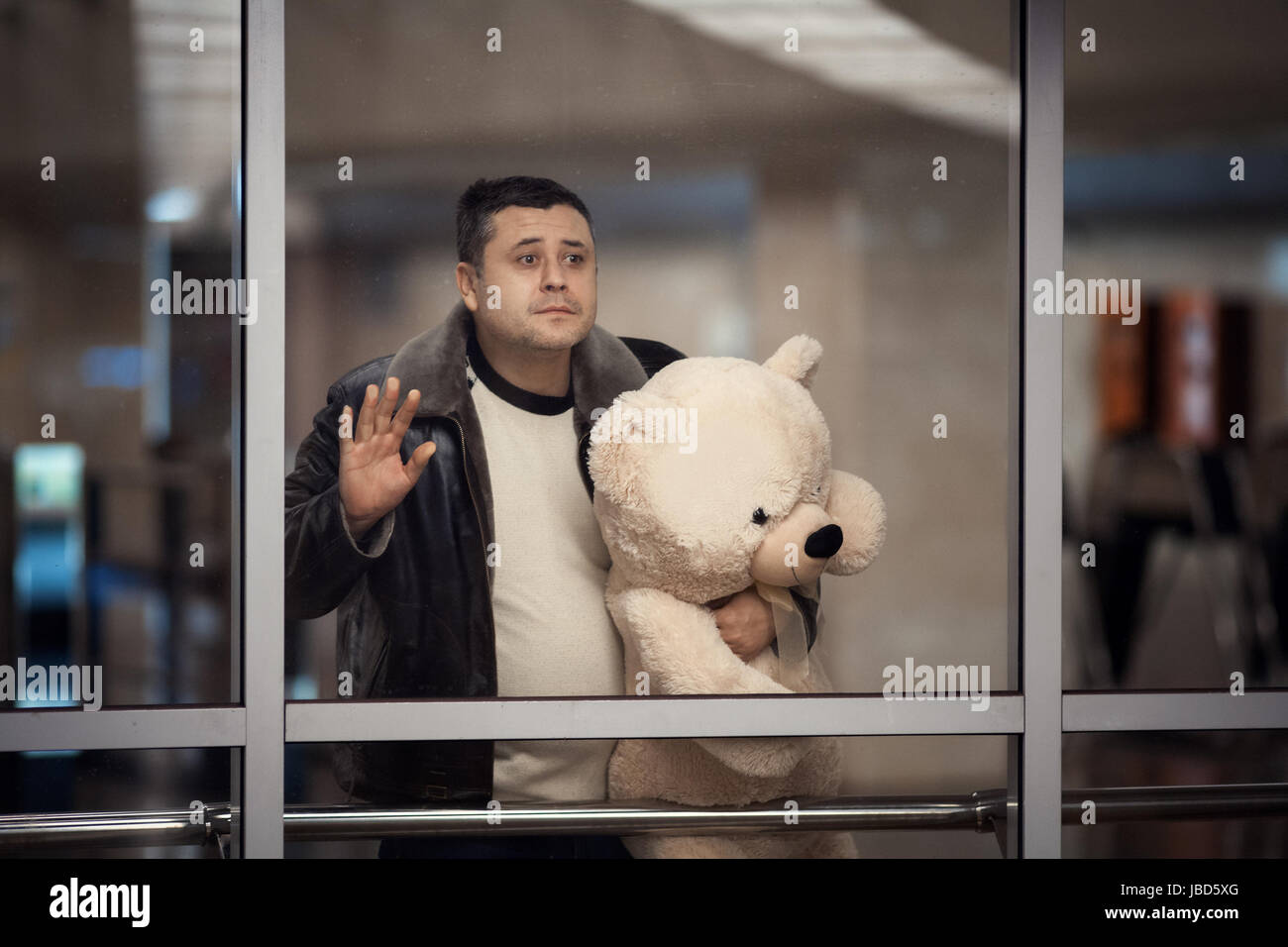 Mann hält ein Spielzeug-Bär und traurig in die Ferne schauen. Er sagt auf Wiedersehen. Stockfoto