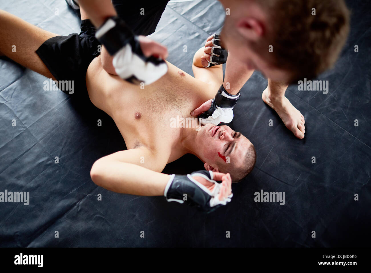 Über Ansicht-Porträt von Profi-Wrestler im Kampf mit Gegner trifft ihn im Gesicht am Boden Stockfoto