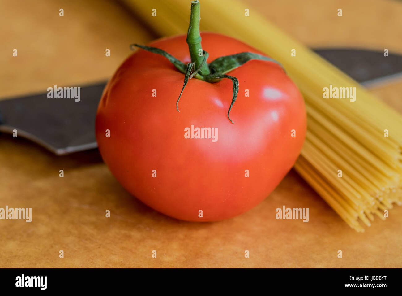 Eine Hand von Spaghetti und ein Messer des Hintergrunds einer Tomate Stockfoto