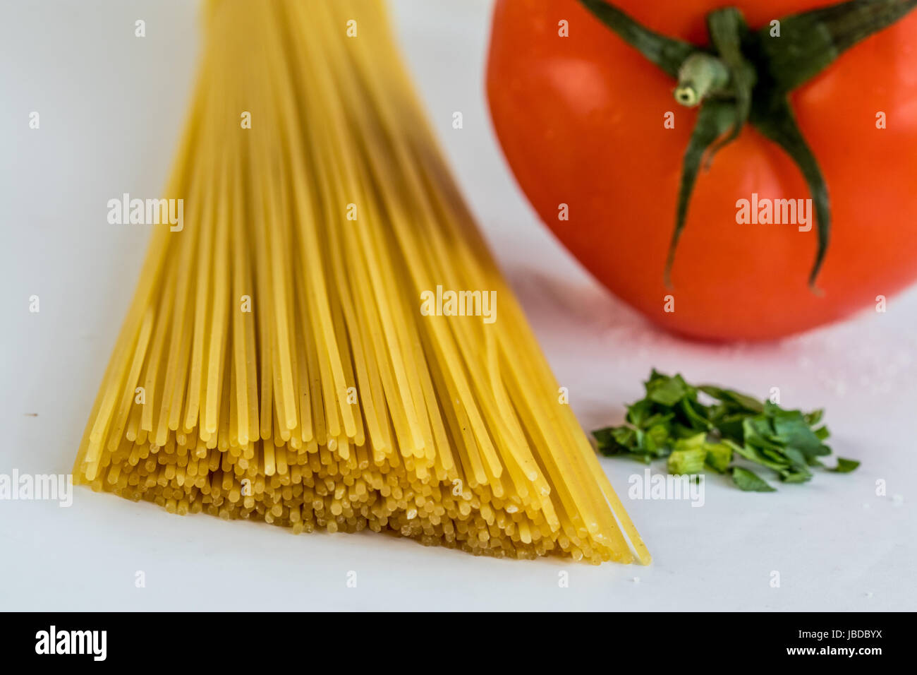 Hand von Spaghetti und einer Tomate Stockfoto
