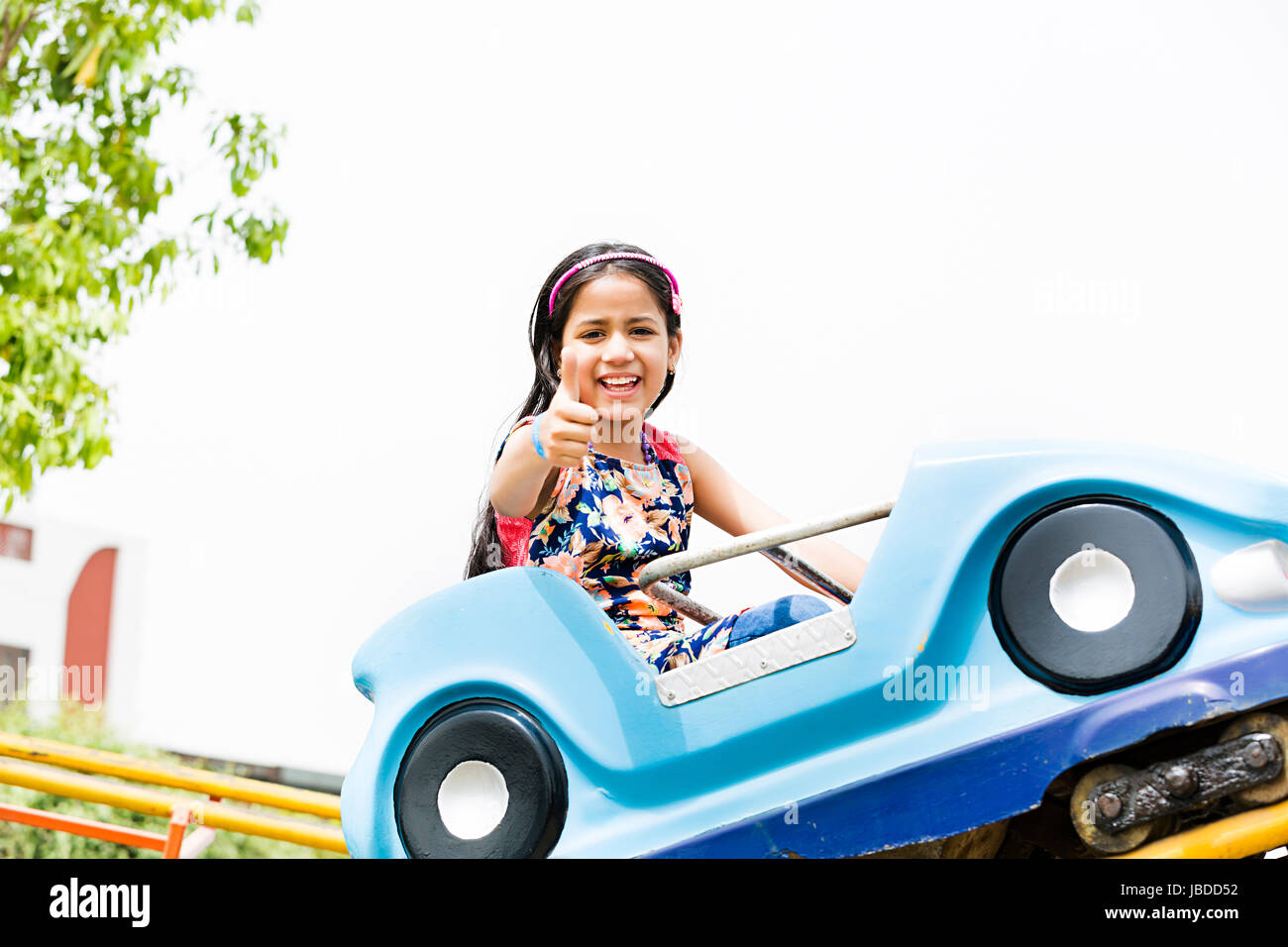 1 indischen Mädchen fahren Auto und zeigen Thumbsup im Vergnügungspark Stockfoto