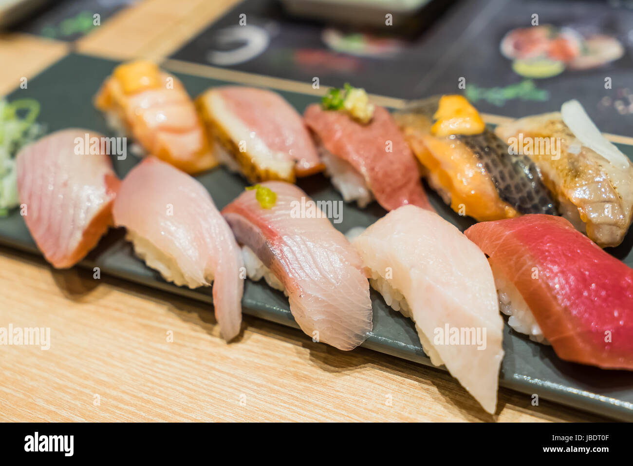 Premium Sushi-Set gehören Engawa, Hamachi, Hotate, Toro, gebratene Ente, Lachs, Seeigel und Tai serviert mit Wasabi und geschweiften Frühlingszwiebeln garnieren Stockfoto