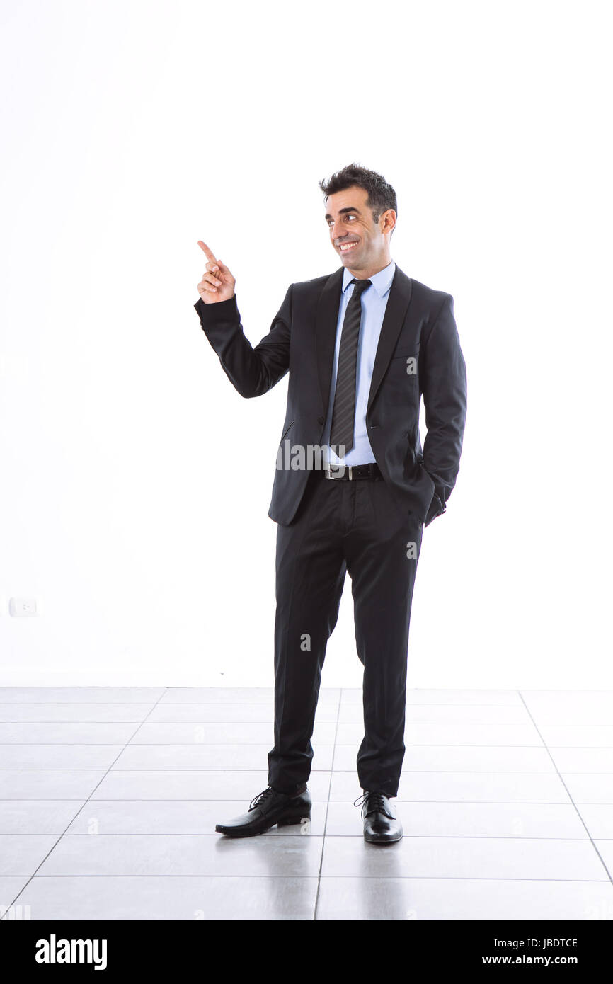 Ein 35-40 Jahre mit Anzug Büro Mann lächelnd Cool modern aussehen zeigenden Finger Seite Studio über einen weißen Hintergrund vollen Schuss erschossen Stockfoto