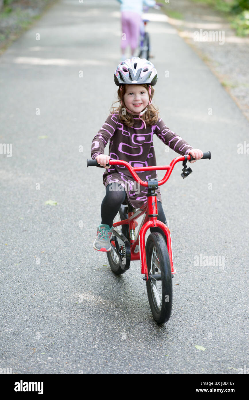 Junge Mädchen Reiten Fahrrad auf gepflasterten Pfad Stockfoto