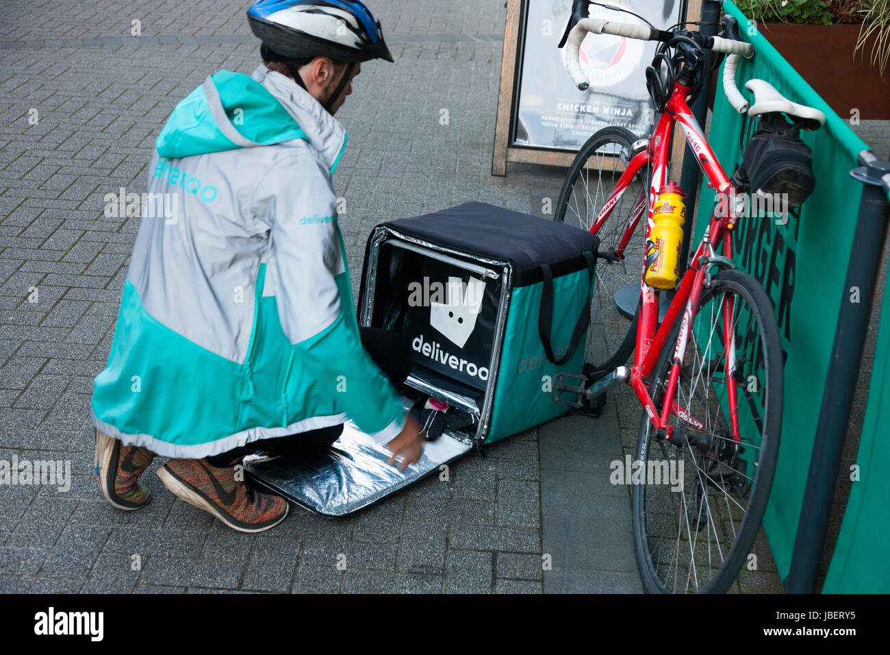 Deliveroo Speisen zum Mitnehmen Kurier Pedal Lieferzyklus / Push Fahrrad Radfahrer machen eine Lieferung laufen in Royal Leamington Spa. GROßBRITANNIEN (88) Stockfoto