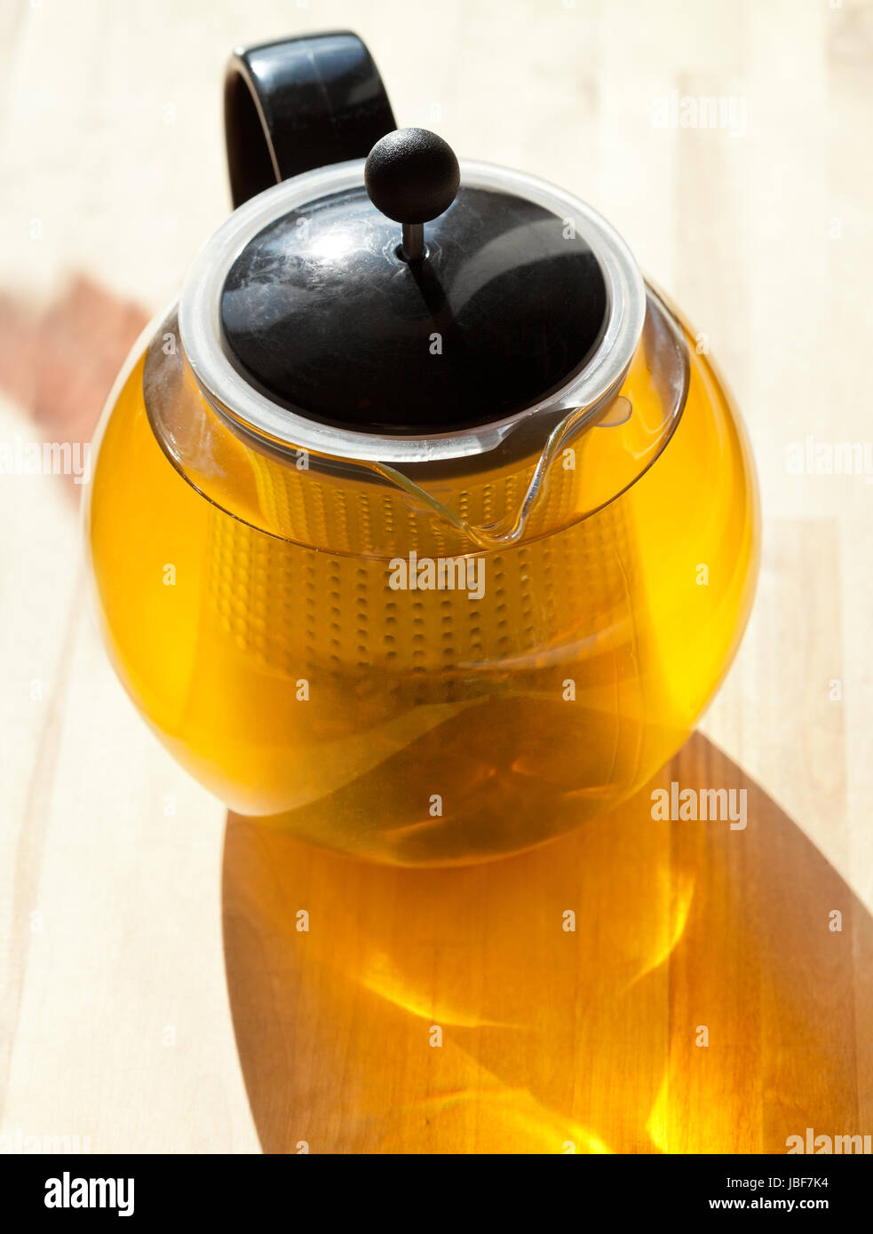 grüner Tee im Glas Teekanne von Sonnenlicht beleuchtet Stockfoto