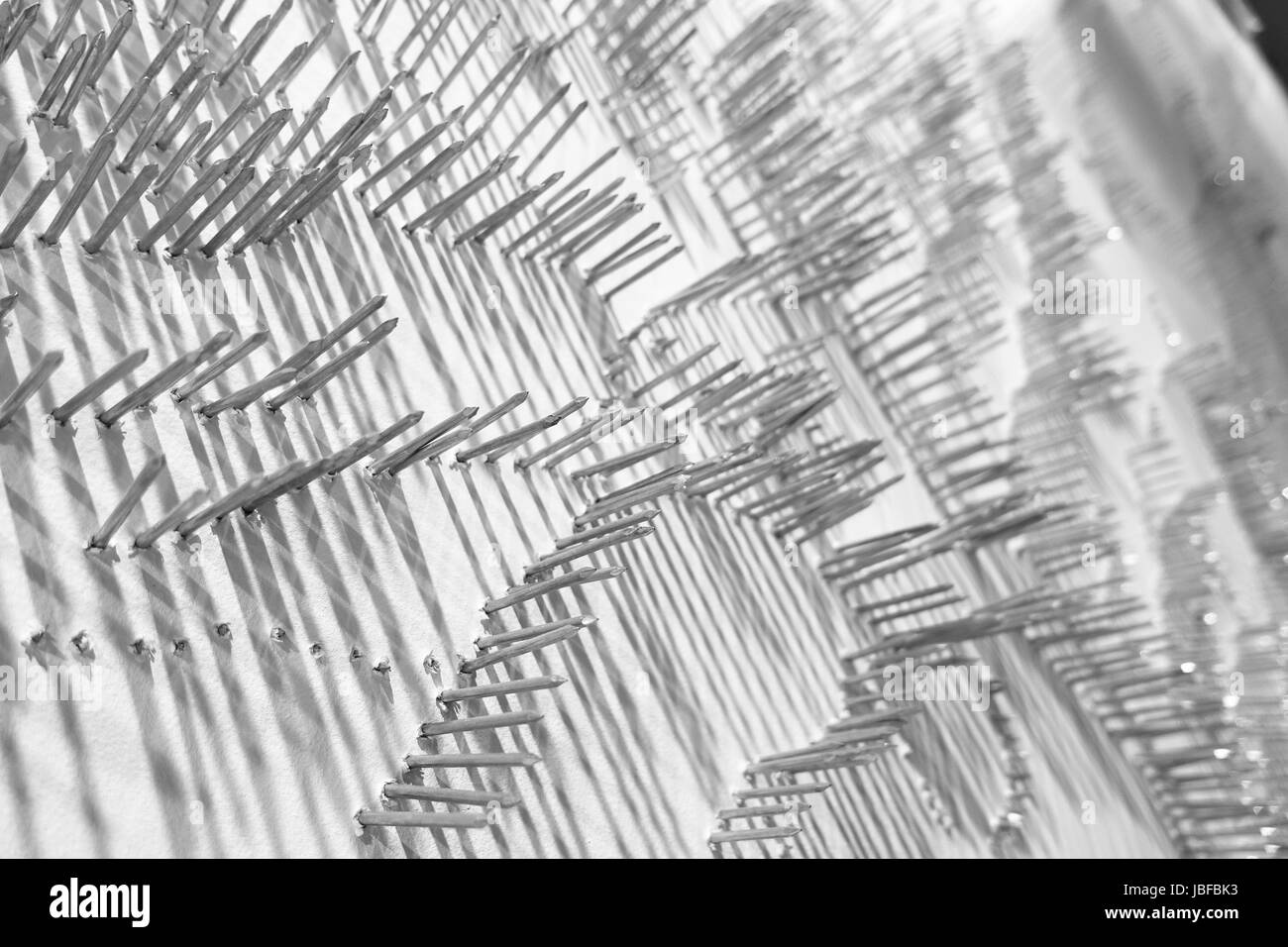 Ein abstraktes Kunstwerk mit Nägeln in den Zeilen ragen aus einem weißen Hintergrund und wirft lange Schatten Stockfoto