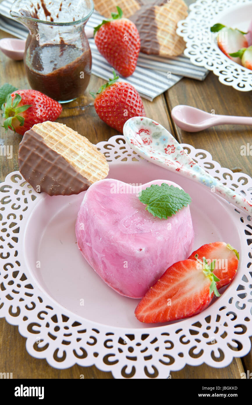 Eis in Herzform Mit Frischen Erdbeeren Auf Rosa Teller Stockfoto