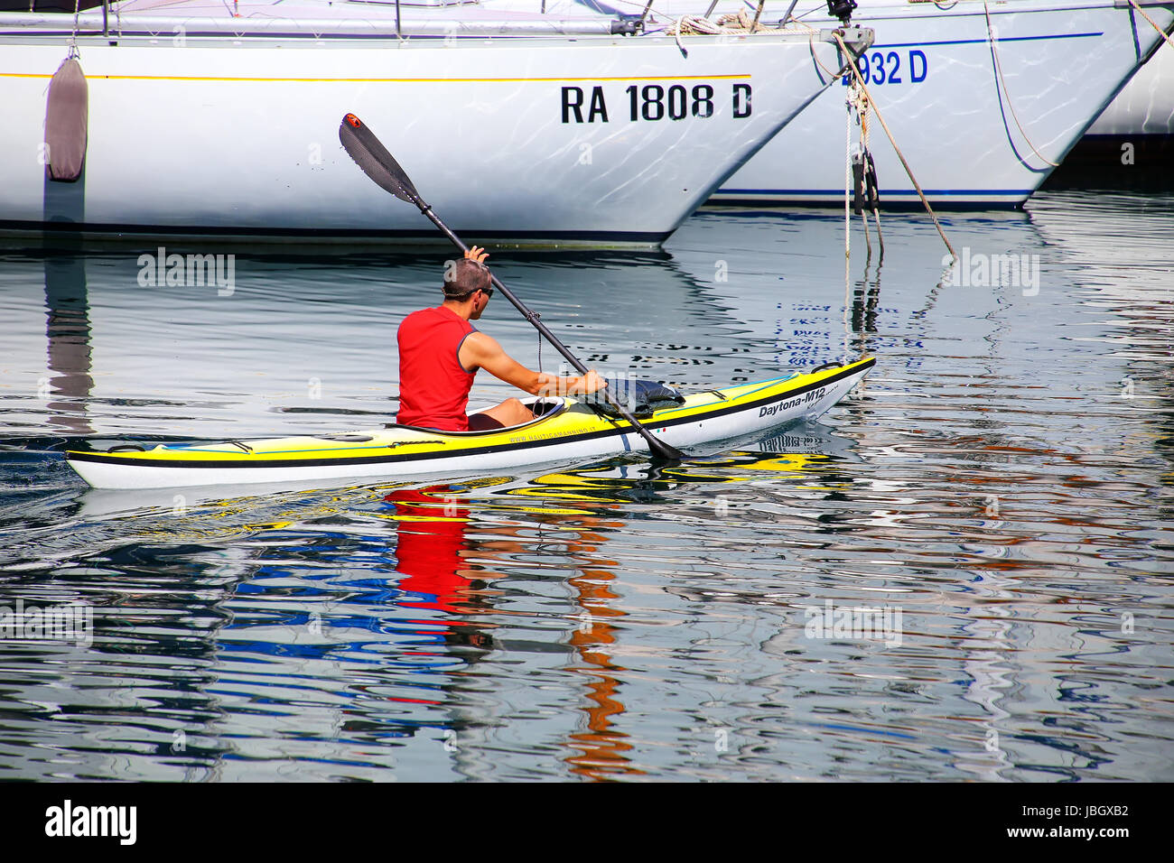 Mann Kajak entlang der Boote in Triest Marina, Italien. Triest ist die Hauptstadt der autonomen Region Friaul-Julisch Venetien Stockfoto