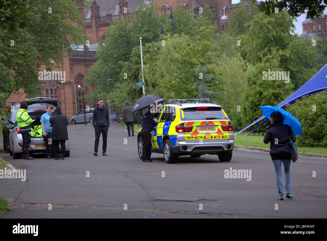 Glasgow, Schottland. 11. Juni. Die beiden Elemente der in diesem Jahre britische Sommer waren anwesend, als Regen auf die West End Festival Big Sunday im Kelvingrove Park strömte. Besucher wurden stark durch die Polizei und private Sicherheitsdienste überwacht. Bewaffnete Polizei patrouilliert Parks im Fahrzeuginneren während Taschen durch private Sicherheitspersonal an den Eingängen durchsucht wurden.  Polizisten patrouillierten Veranstaltungsort zu Fuß oder Fahrrad.  Kredit Gerard Fähre/Alamy Live-Nachrichten Stockfoto
