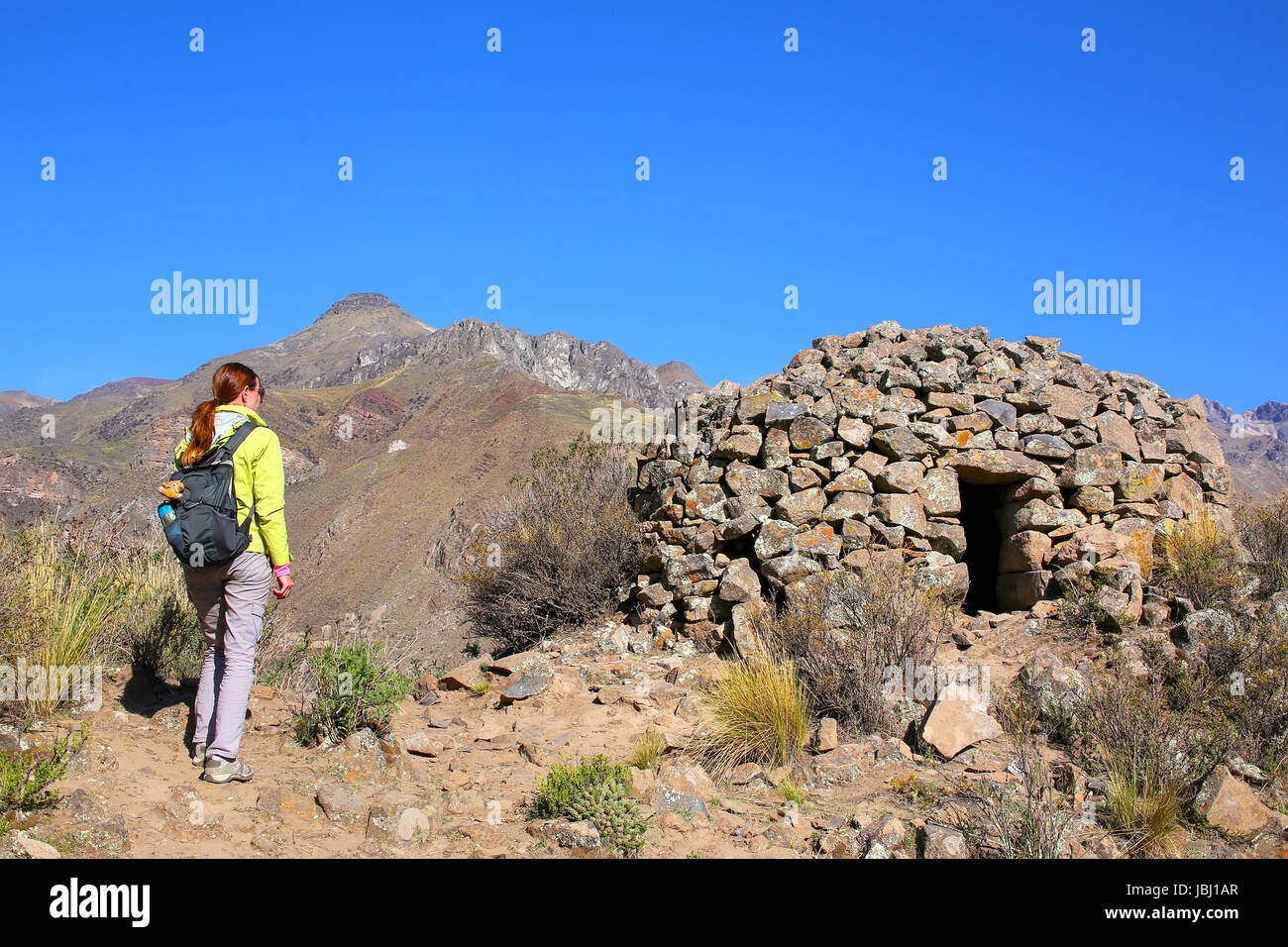 Touristen auf der Suche im Pre-Inka-Runde House benannt Colca in der Nähe von Chivay in Peru. Colcas sind kreisförmige Stein-Strukturen für die Lagerung von Lebensmitteln oder Bestattungen verwendet. Stockfoto