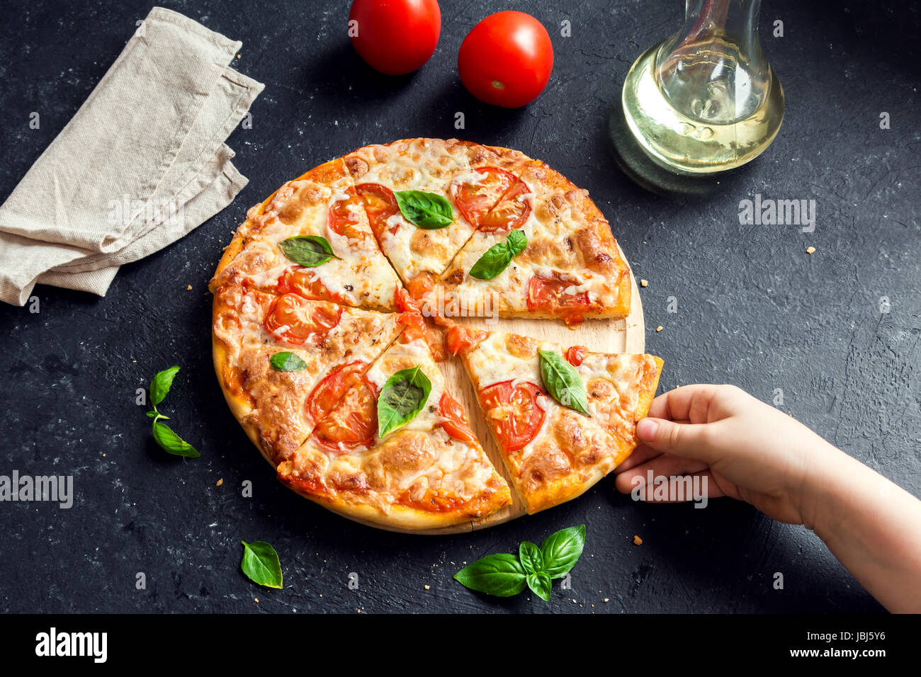 Menschen Hand die Scheibe der Pizza Margherita. Pizza Margarita und Kinderhand hautnah. Stockfoto