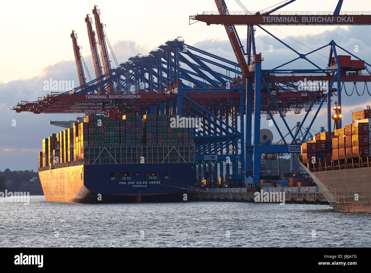 Das Containerschiff CMA CGM Jules Verne ist am terminal Hamburg Burchardkai am Mai 2014 03 am Abend geladen/entladen. Das warme Licht der untergehenden Sonne spiegelt sich auf dem Schiff. Stockfoto