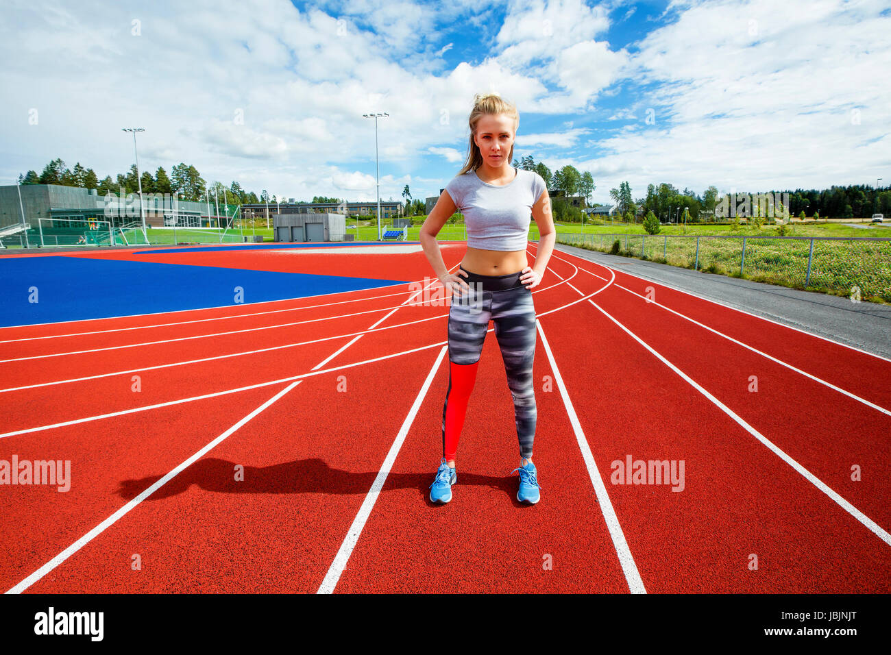 Sportliche Frau stehend mit Händen auf den Hüften auf Laufstrecken Stockfoto