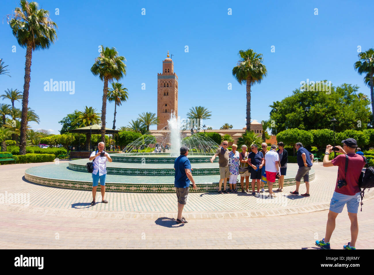 Marrakesch, Marokko - 12. Mai 2017: Eine Gruppe von Touristen fotografieren von einander vor dem Brunnen in Koutoubia Gärten mit der Koutoubia Stockfoto