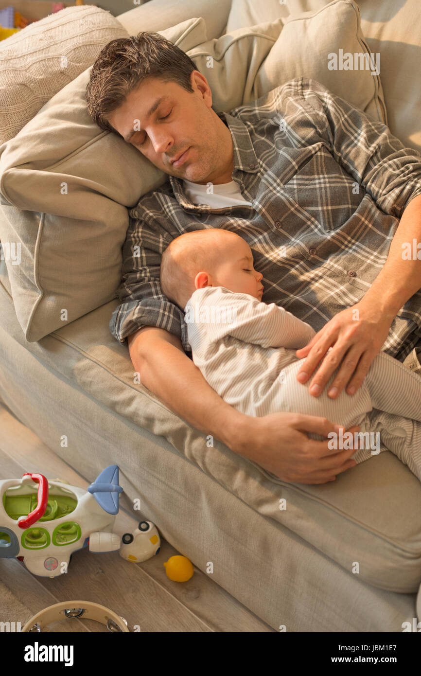 Vater und Baby Sohn auf dem Sofa schlafen erschöpft Stockfoto