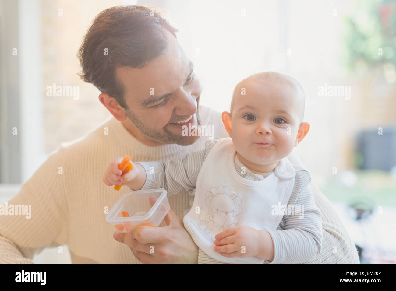 Porträt, Lächeln, niedlichen Baby Sohn und Vater Essen Karotten Stockfoto