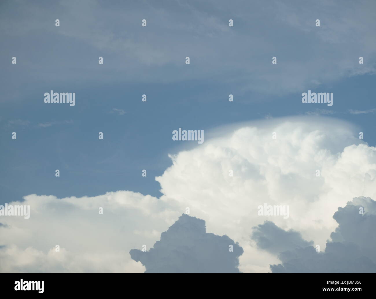 blauer Himmel mit geschichteten weißen und grauen Wolken Stockfoto