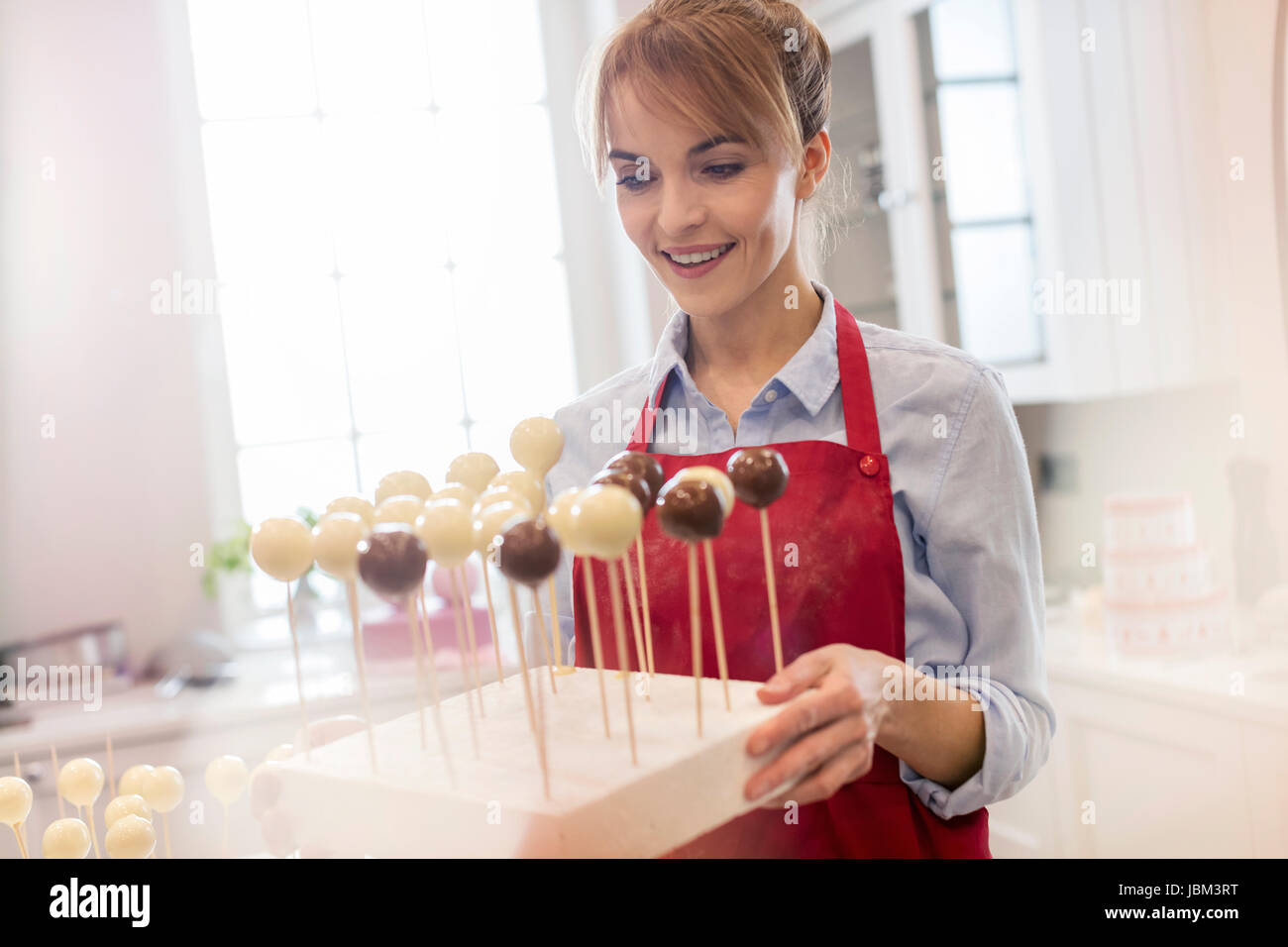 Lächelnd weibliche Caterer backen Kuchen pops in Küche Stockfoto